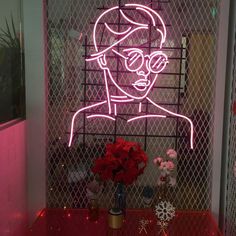 a pink neon sign with a man's face on it in front of a window