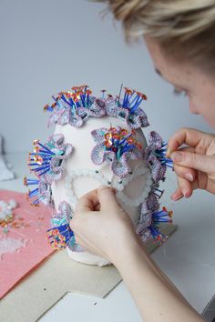 a woman is decorating a cake with colorful decorations