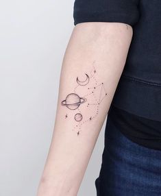 a woman's arm with a small saturn tattoo on the left side of her arm