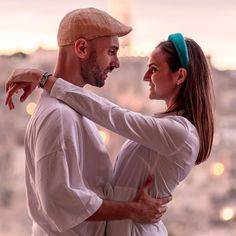 a man and woman standing next to each other in front of a cityscape