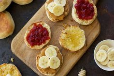 bread with peanut butter and banana slices on a cutting board next to honey and jam