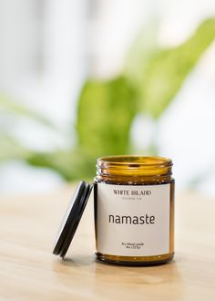 a jar of white island namaste sits on a table next to a plant