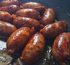 some sausages are cooking in a pan on the stove