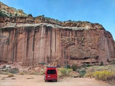 a red van parked in front of a large rock formation