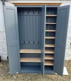 an open storage cabinet with shelves and doors on the outside wall, in front of a white brick building