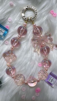 a necklace with pink beads and charms on top of a white furnishing area