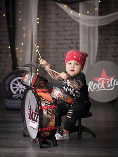 a little boy sitting on top of a drum with a red bandanna around his head