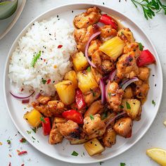 a white plate topped with chicken and pineapples next to rice