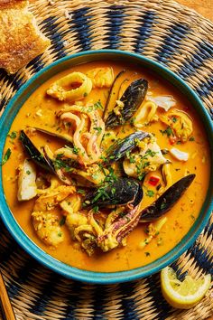 a bowl filled with seafood and mussels next to bread