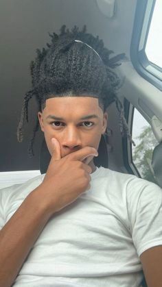 a young man with dreadlocks sitting in the back seat of a car looking at the camera