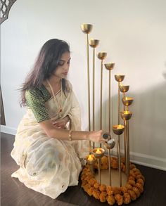 a woman kneeling down next to a tall candle holder