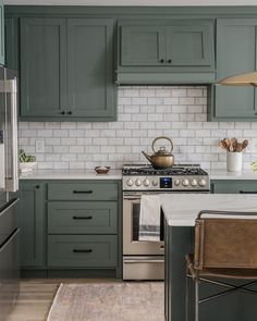 a kitchen with green cabinets and white tile backsplash