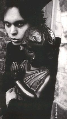 black and white photograph of a young man holding a statue in front of a brick wall