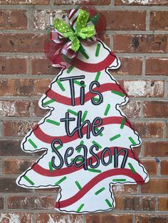 a christmas tree sign on the side of a brick wall that says tis the season