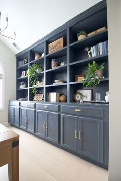 an empty room with blue bookcases and plants on the top shelf in front of it