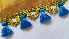 blue tassels are hanging from the side of a yellow and gold pillow cover