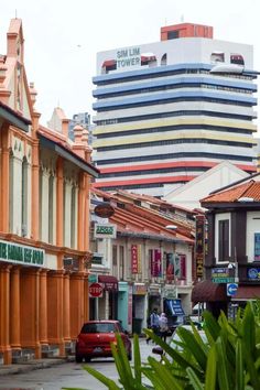 a city street filled with lots of tall buildings next to green plants and trees on the side of the road