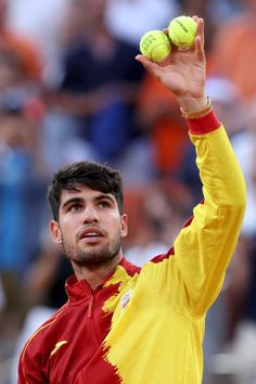 a man holding two tennis balls up in the air