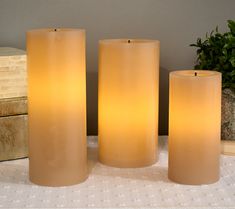 three lit candles sitting next to each other on a table