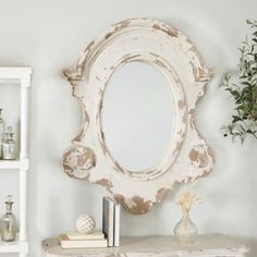 a white table topped with a mirror next to a shelf filled with books and vases