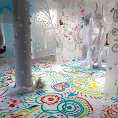 an art installation with white and multicolored paper on the floor, surrounded by plastic sculptures