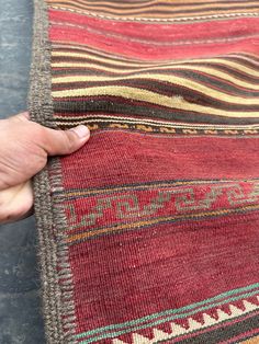 a person is holding onto a rug with different colors and patterns on it's surface