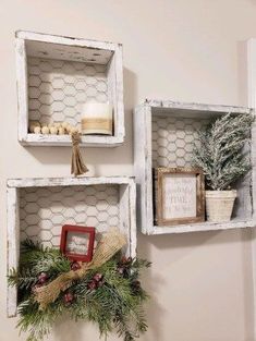 two white shelves decorated with christmas decorations and greenery, one is hanging on the wall