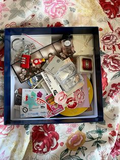 the contents of a drawer are displayed in a shadow box on a floral print sheet