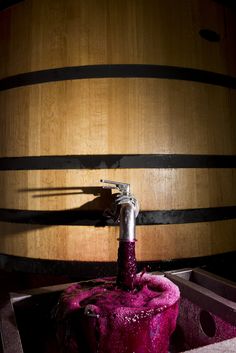 a purple substance is spewing from a faucet in front of a wooden barrel