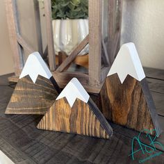 three wooden mountains sitting on top of a table next to a vase with flowers in it