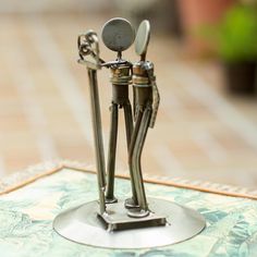 two metal figurines are holding spoons on top of a table with a tile floor in the background