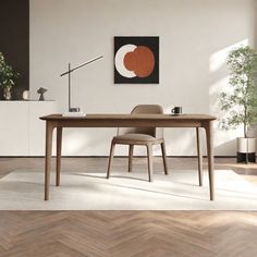 an empty room with a table and chair in it, next to a plant on the floor