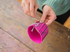 a woman is holding a pink hat with a tassel on it and threading the top