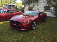 a red mustang parked in front of a house