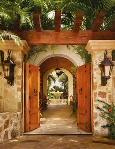 an open door leading into a courtyard with palm trees and potted plants on either side