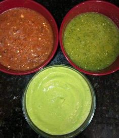 three bowls filled with different colored sauces on top of a black counter next to each other