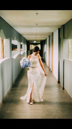 a woman in a white dress is walking down the hallway with her bouquet on her hand