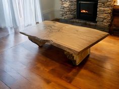 a wooden table sitting on top of a hard wood floor next to a fire place