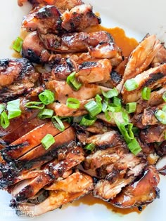 grilled chicken with green onions and sauce on a white plate