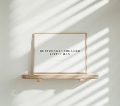 a wooden shelf with a framed print on it that says be strong in the lord, little man