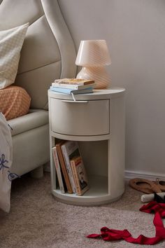 a white night stand with books on it