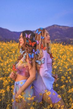 two beautiful women walking through a field with butterflies on their hair and one has her back to the camera