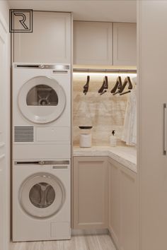 a washer and dryer in a small room with white cupboards on the wall