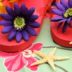 purple flowers are placed on red flip flops with yellow starfish in the foreground