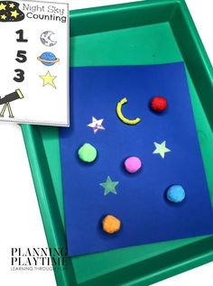 a blue tray with felt stars and moon shapes on it next to a counting game