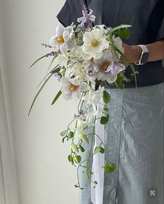 a man holding a bouquet of white and purple flowers