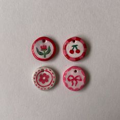 three red and white buttons with designs on them sitting next to each other in front of a white background