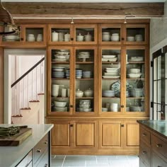 a kitchen filled with lots of wooden cupboards and dishes on top of it's shelves