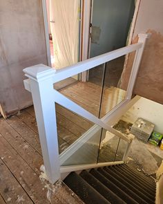 an open glass door on the side of a wooden floor next to a stair case