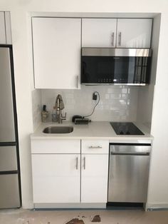 a kitchen with white cabinets and silver appliances